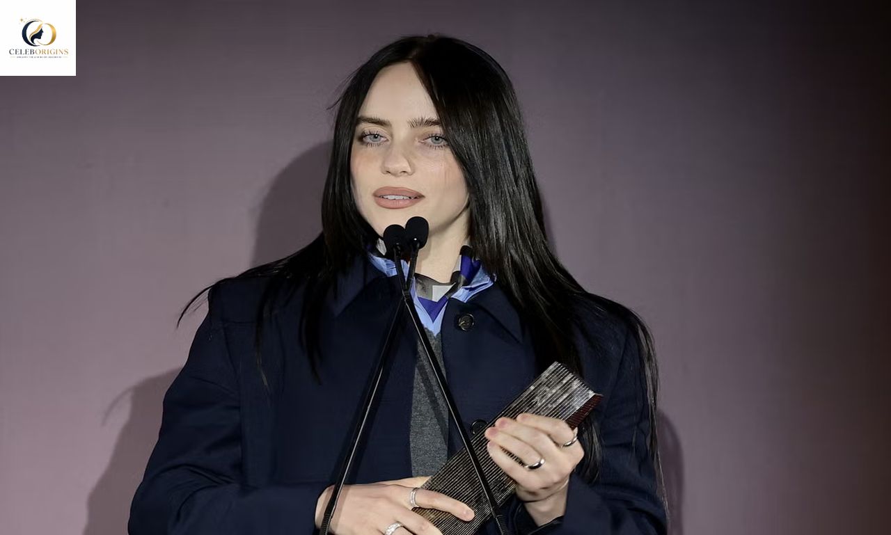 Woman speaking at a microphone during a public event, holding a small book or card in her hands.